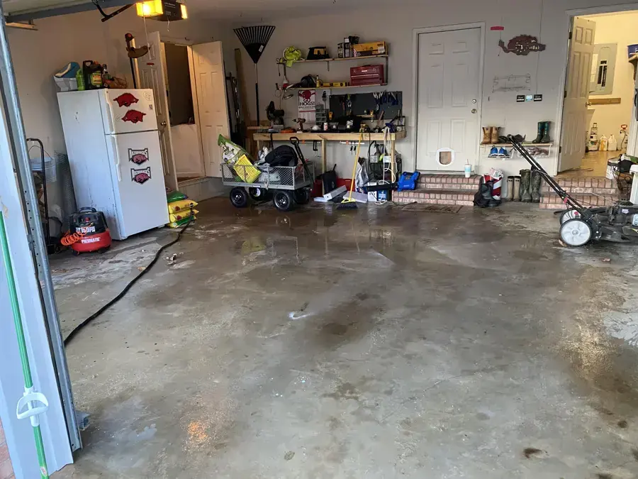 A garage floor still wet after water was pushed out the open door