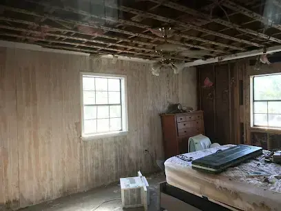 A bedroom with the ceiling and wall paneling removed after storm water