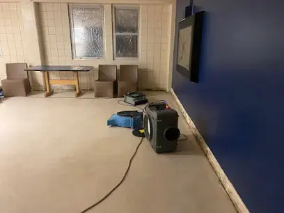 Dehumidifier and air mover running on the bare floor of an emptied Gretna room