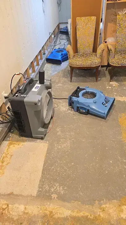 Dehumidifier and air mover drying a room with the flooring removed, a Gretna home dry-out