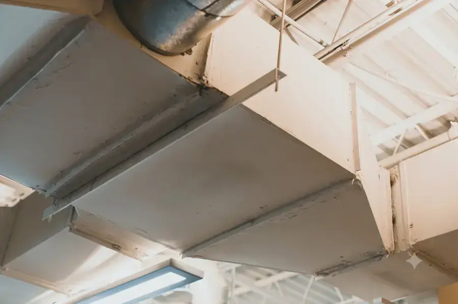 Ductwork and a water-stained ceiling below an attic air handler