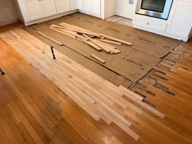 Kitchen hardwood flooring pulled up after a leak near the cabinets