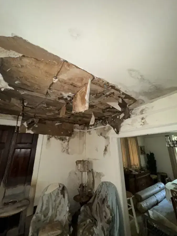 A ceiling torn open and sagging after a roof leak soaked it from above